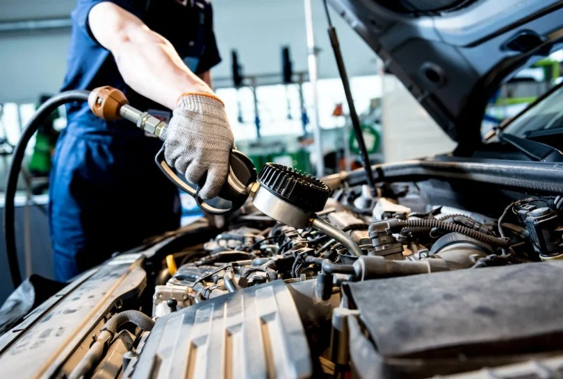 Mechanic performing maintenance on car engine, 247lemonlaw