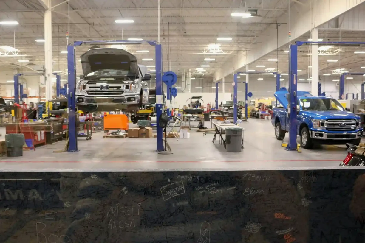 Spacious auto repair shop with multiple Ford trucks on hydraulic lifts, 247lemonlaw