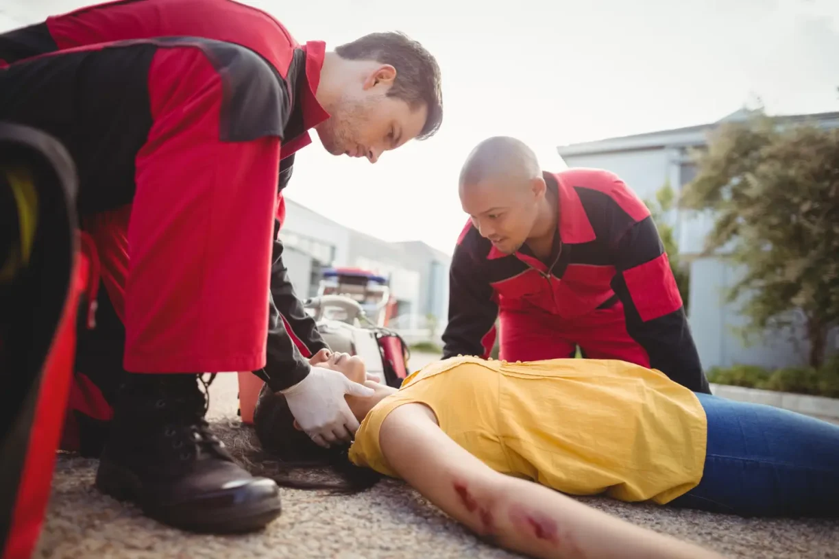 Paramedics assisting a seriously injured woman at an accident scene, showing the urgency of medical attention after personal injury.