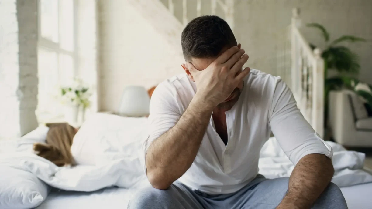 Distressed man sitting on a bed with his head in his hands, representing emotional distress and mental anguish in personal injury cases.