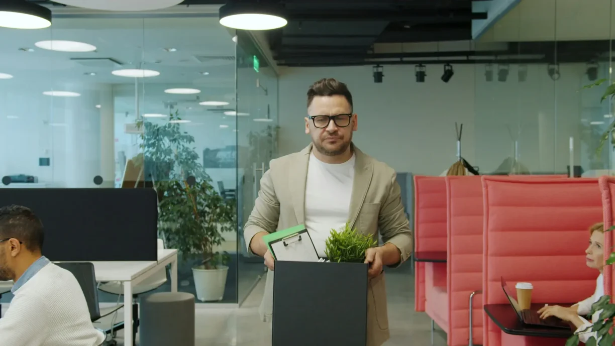 Employee carrying personal belongings after losing a job, representing wrongful termination and employment disputes.