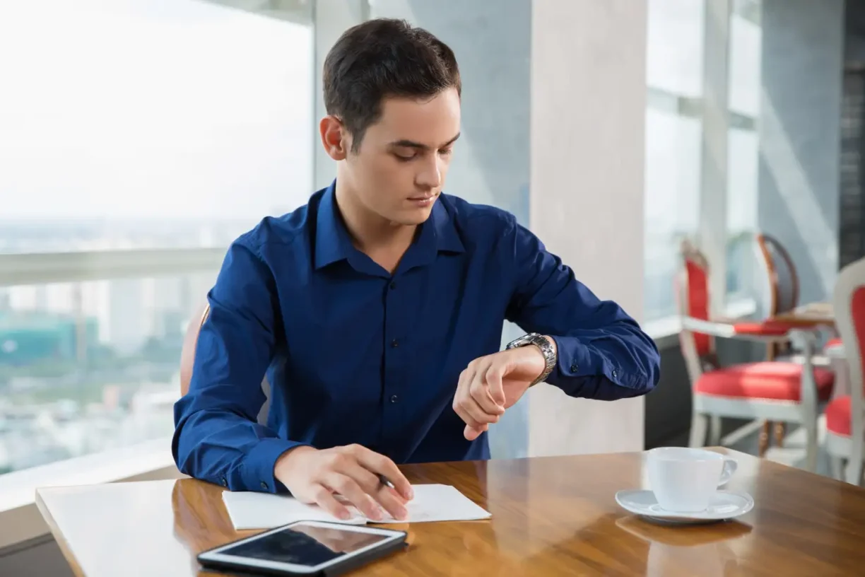 Employee checking his watch while waiting at work, representing delays and unpaid wage issues.
