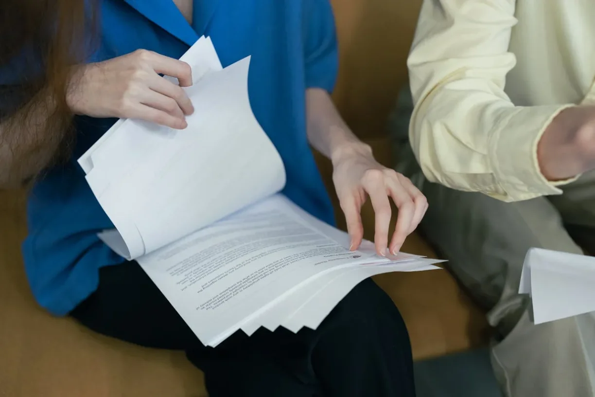 Individuals examining paperwork together, illustrating legal review, evidence preparation, or case documentation.