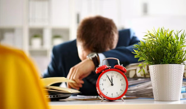 Overworked employee exhausted at his desk, illustrating stress and burnout from excessive working hours.
