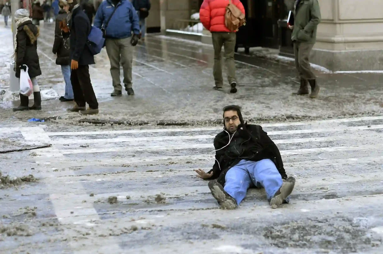 Pedestrian injured after slipping on an icy crosswalk, showing the dangers of unsafe winter sidewalks.
