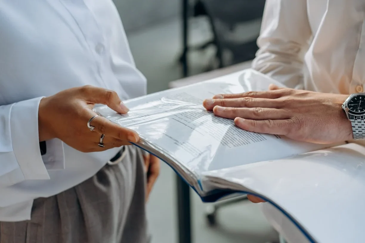 Two people reviewing and signing legal documents, representing contracts and formal agreements.