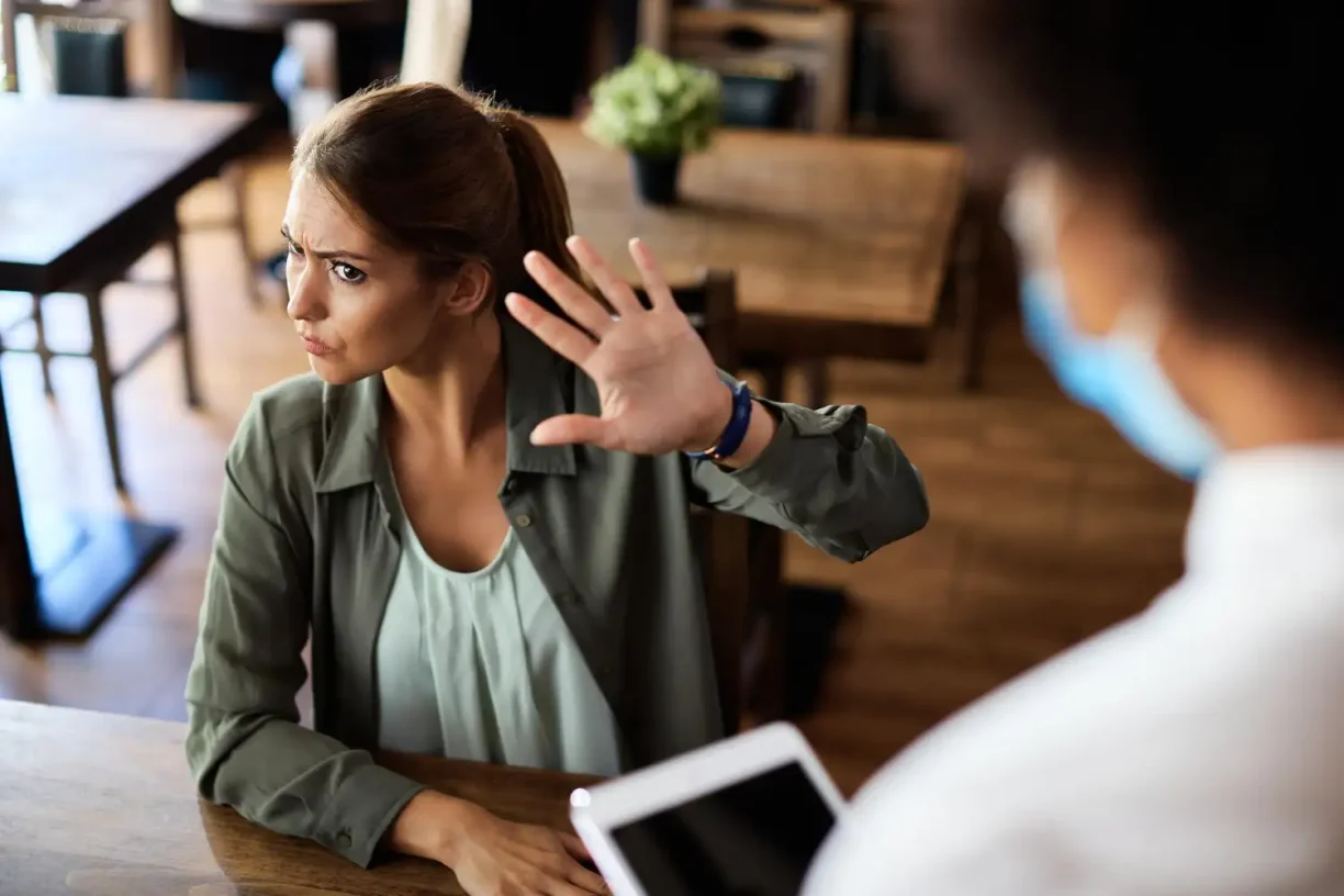 Woman raising her hand to stop unwanted behaviour, representing workplace harassment and personal boundaries.