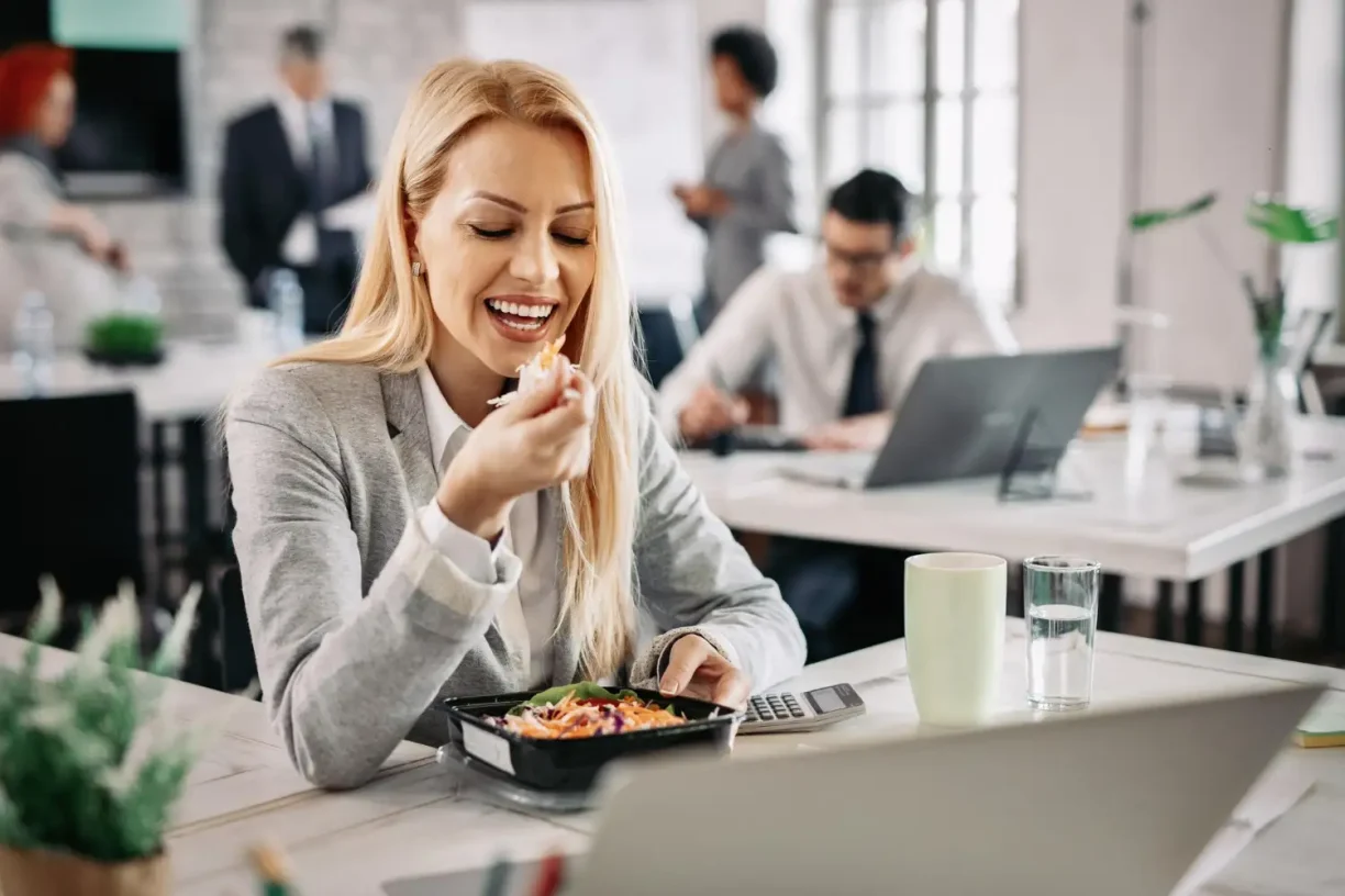 Employee eating a healthy lunch at the office, highlighting workplace wellness and work-life balance.
