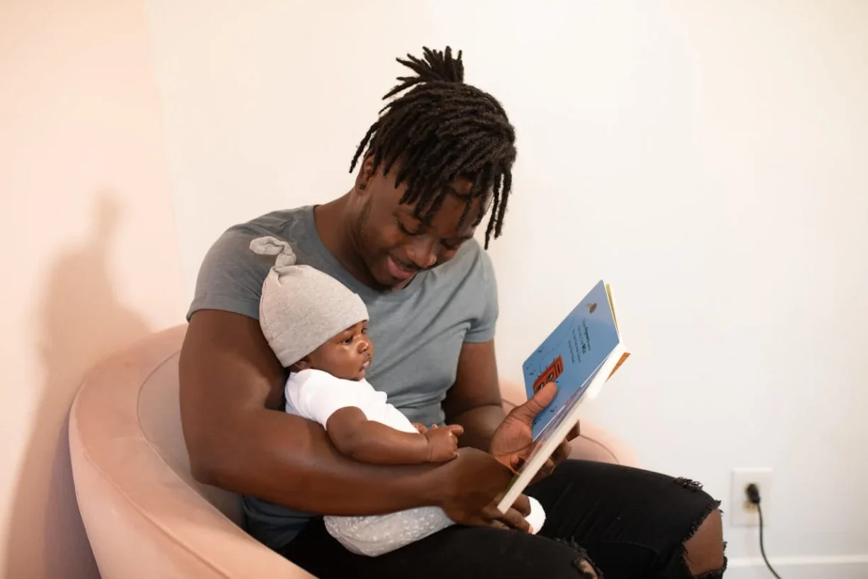 Father on paternity leave reading to newborn, illustrating rights protected under california paternity leave laws